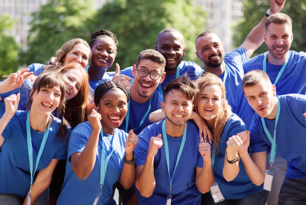 Group of smiling volunteers wearing matching blue shirts and lanyards